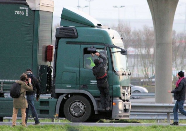 A migrant threatens a truck driver with a lump hammer in Calais in December. A shocking reminder, as strike action is threatened again, that none of the issues which caused such problems in the summer are done and dusted just yet. Photo via Les Calaisiens en Colere/Facebook.